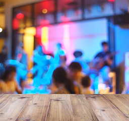 Wooden top table over blurred background of music band in restaurant for display the products.