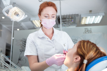 woman dentist looks at patient in armchair