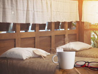 Cup of coffee and red glasses on wooden table in the morning of vintage bedroom .