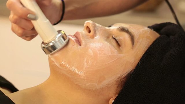 Rejuvenating facial treatment. Model getting lifting therapy massage in a beauty SPA salon. Exfoliation, Rejuvenation And Hydratation. Model and Doctor. Cosmetology. Close up, selective focus.