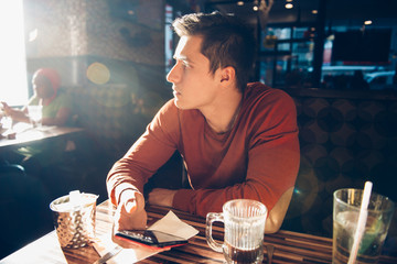 Man having morning breakfast with coffee in diner cafe and using his mobile phone