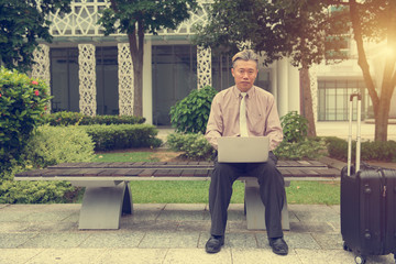 asian senior using laptop outdoor