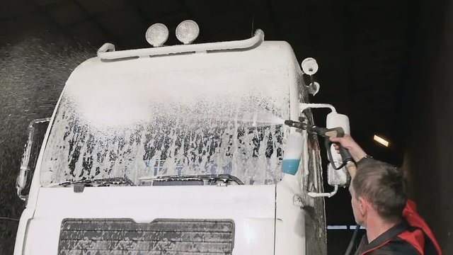Workep applies cleanser on windshield of truck in slowmotion
