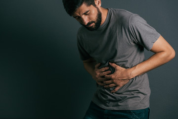 Young man suffering from stomach ache standing