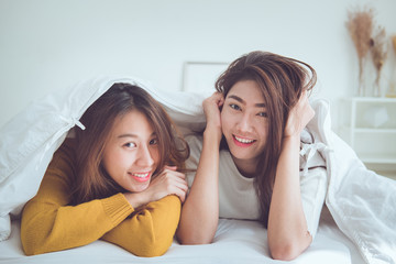 LGBT. Lovely lesbian couple together concept. Couple of young women lying and using smart phone on the bed after wake up.