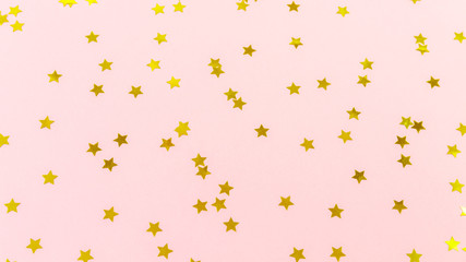 Golden star sprinkles on pink. Festive holiday background. Celebration concept