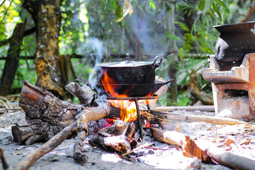 Burning firewood in the fireplace with old black cooking pot and smoke