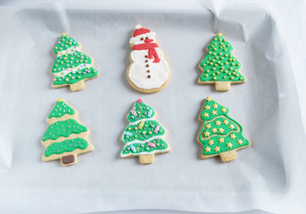 Festive Christmas snowman Cookie with decorated trees on white paper.