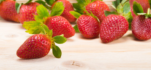 strawberries scattered on a light wooden background