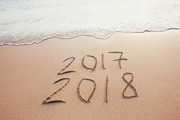 new year change 2017 to 2018, calendar dates written on the sand of beach