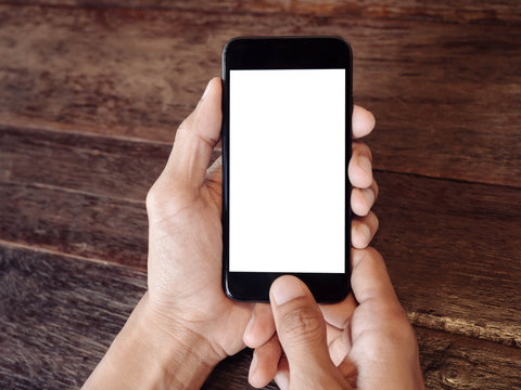 Closeup Of Man's Hand Is Holding A Black Cell Phone With Blank White Screen That You Can Put Any Ideas In This Space On Wood Table At Coffee Cafe 