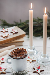 Christmas and new year holiday celebration concept background. Cup of cocoa with marshmallow, homemade cookie, lighted candles, xmas tree decoration on wooden table.