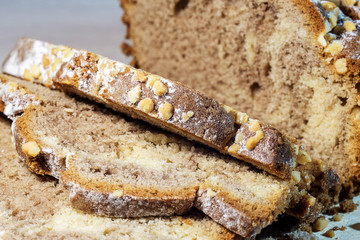 Freshly baked homemade cake, decorated on top with powdered sugar, cut into slices, on a wooden stand