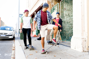 Fototapeta premium Teenage friends walking at the street with skateboards