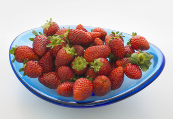a blue glass bowl of fresh ripe strawberries