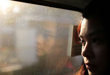 girl face watching out the train with the evening sun bright