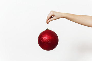 Christmas concept with female hand and big red round shiny ball - christmas tree toy isolated on white background close up
