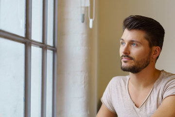 Obraz premium mann schaut nachdenklich aus dem fenster