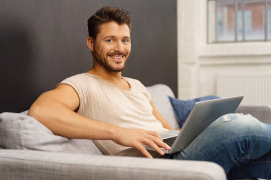 mann sitzt auf dem sofa und surft im internet