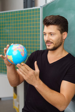 lehrer steht im klassenzimmer und hält einen globus in der hand