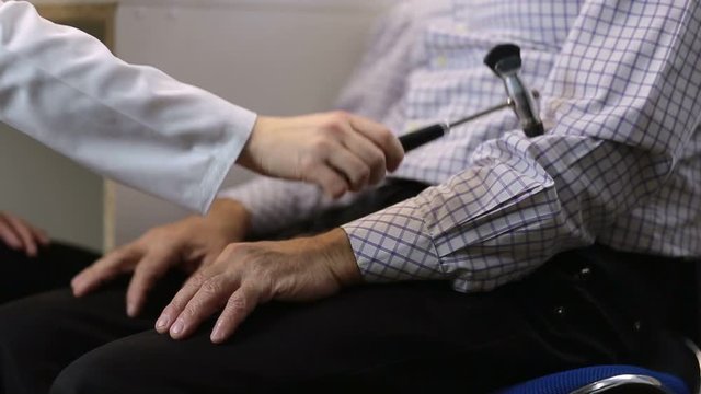 Neurologist checking arm reflex of male patient