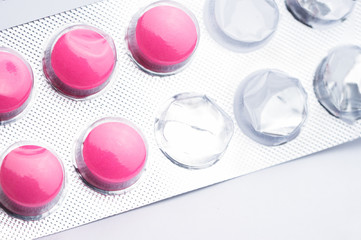 Top view of used blister pack of magenta tablets, medical pills in silver foil pack on white background.