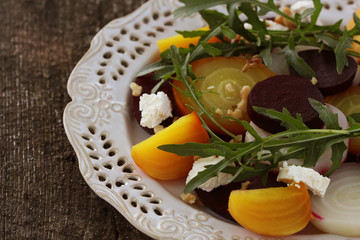 Healthy Beet Salad with red, white, golden beets, arugula, nuts, feta cheese on wooden background