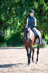 Young teenage girl riding horseback at equestrian school