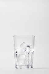 Glass with ice cubes on white background