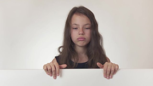 Beautiful girl teenager looks at a poster with information and expresses frustration and resentment on white background stock footage video.