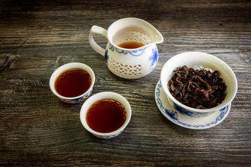 black tea in traditional chinese cups and teapot on wooden table