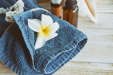 Blue spa towel with exotic flower and essential oil on wood background. Spa and wellness concept. Copy space.