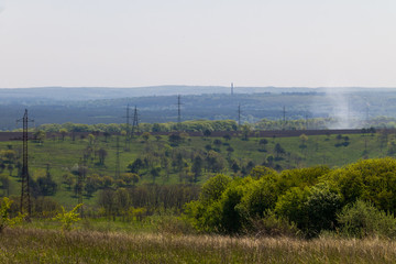 Fototapeta na wymiar Landscape with power line, green hills and trees