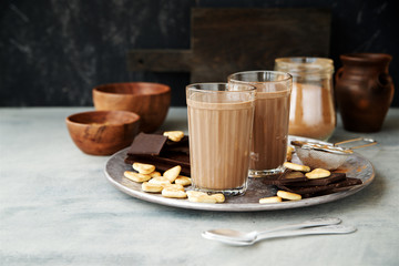 Hot milk chocolate or cocoa in glasses with ingredients in the background 
