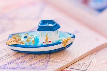 Small blue toy boat lying on the passport page with visa stamps