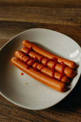 Delicious sausages with ketchup on a white plate on the kitchen. man food.