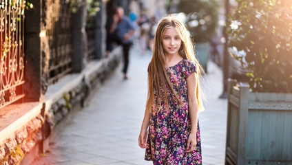 Fototapeta premium Beautiful little girl on a city street, evening fashion shot