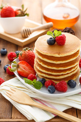 Mixed berry pancake with honey on wooden table