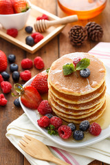 Mixed berry pancake with honey on wooden table