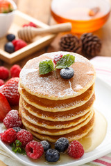 Mixed berry pancake with honey on wooden table