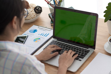 Over the shoulder shot of an Asain boy typing on a computer laptop with a key-green screen. Woman hand typing laptop with green screen. © pixindy