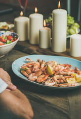 Holiday celebration table setting with snacks. Salad, shrimps and candles on wooden table