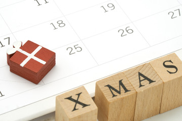 Red gift wood box on Calendar with wood word X MAS. Day 25 meets Christmas Day using as background Christmas concept with copy space.