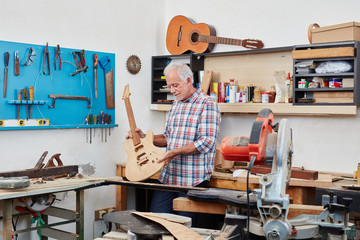 Senior Handwerker baut E-Gitarre in Werkstatt