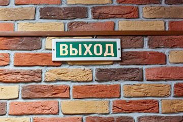 plaque with the inscription exit in Russian on a brick wall above the door