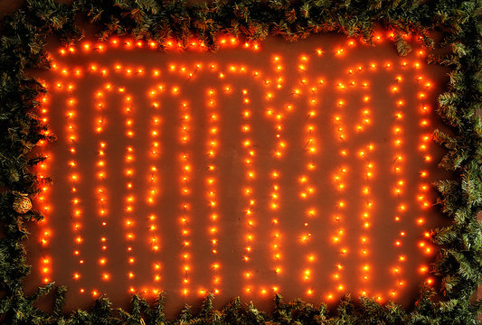 Bright Orange Christmas Lights On A Wooden Wall In A Frame Of Fir Branches