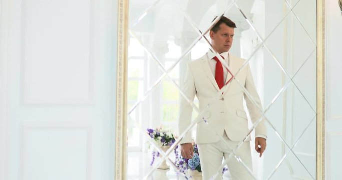 groom looks in the mirror / businessman looks at his reflection in the mirror
