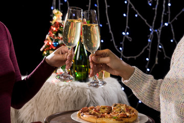 Beautiful two women holding glasses with champagne celebrating Christmas and gift boxes at corporate party and christmas lights, New Year Frame for your text