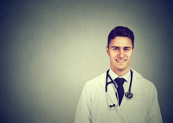 Portrait of a smiling young male doctor on gray wall background