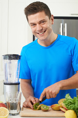 Fototapeta premium Male Athlete Making Juice Or Smoothie In Kitchen